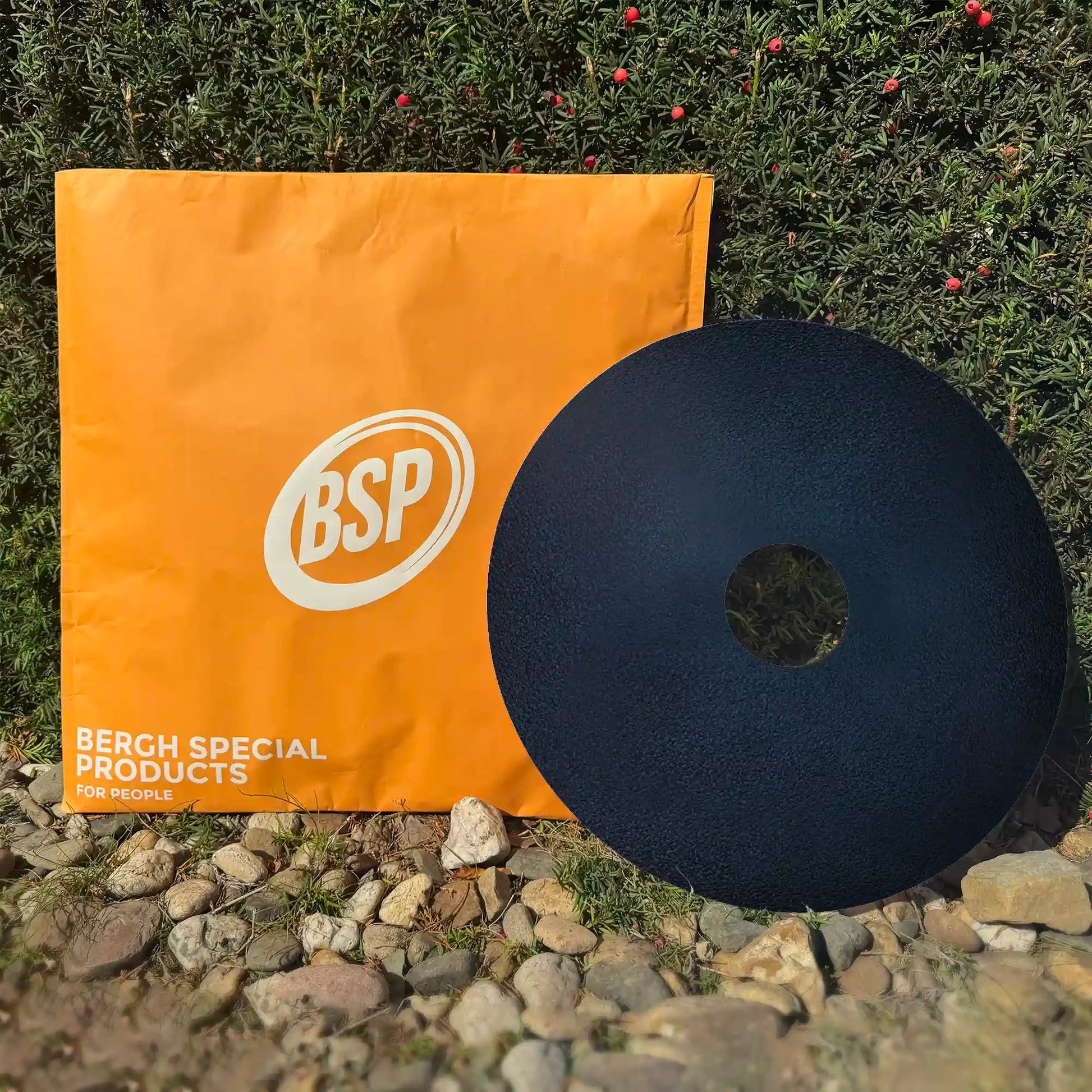 Black sport wheelchair spoke guard next to orange BSP packaging outdoors near green wall