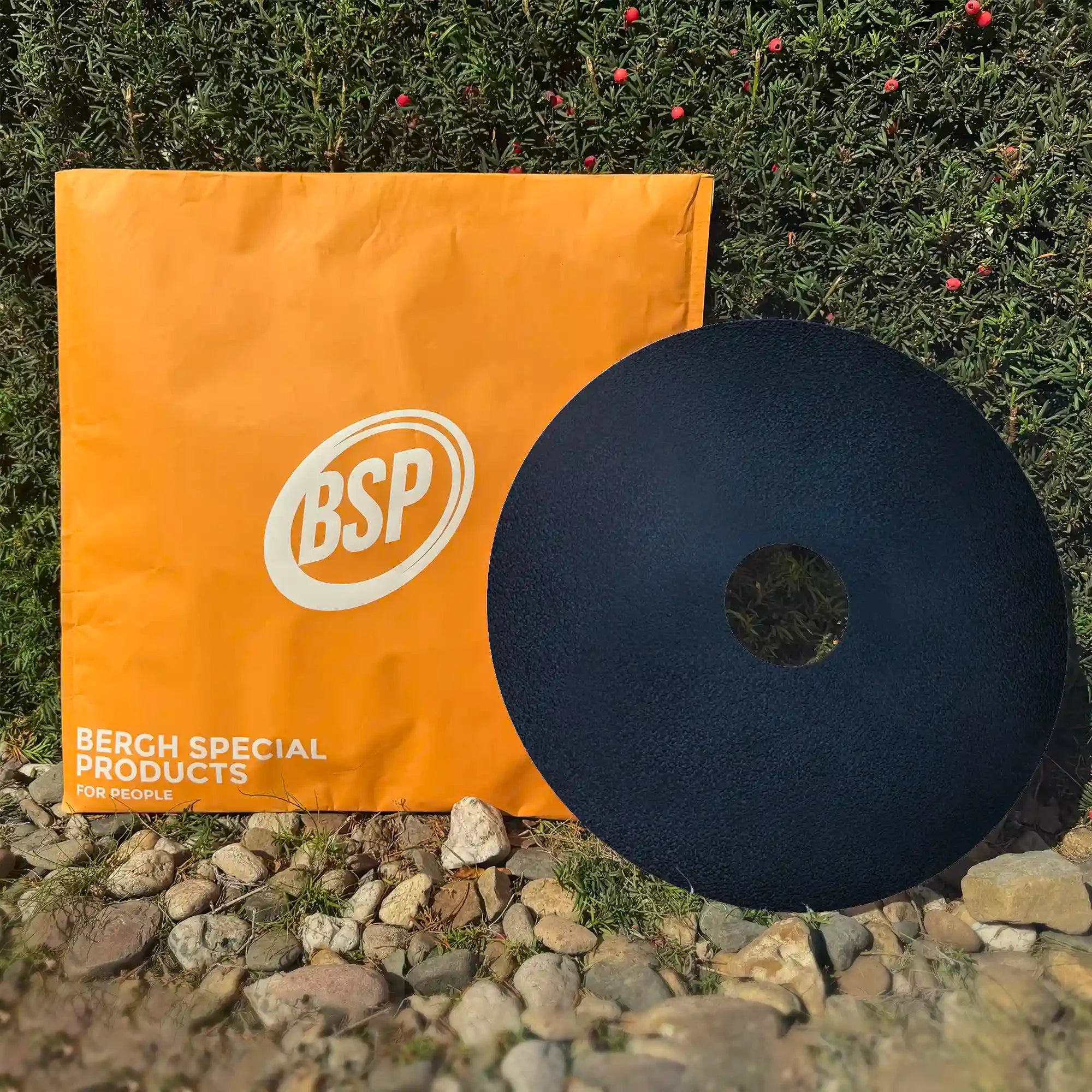 Black sport wheelchair spoke guard next to orange BSP packaging outdoors near green wall