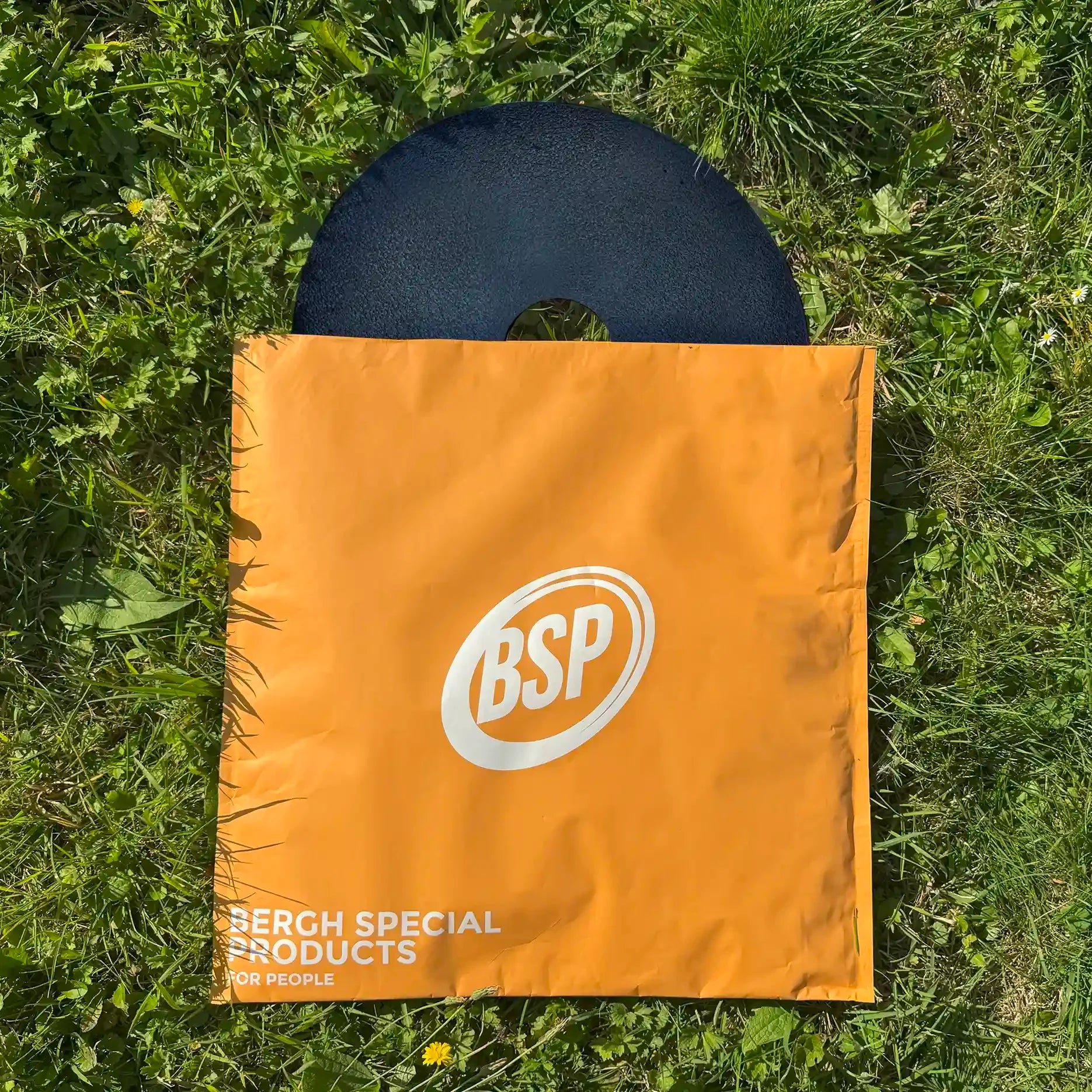 Wheelchair sport spoke guard partially inside an orange BSP carrying case on grass