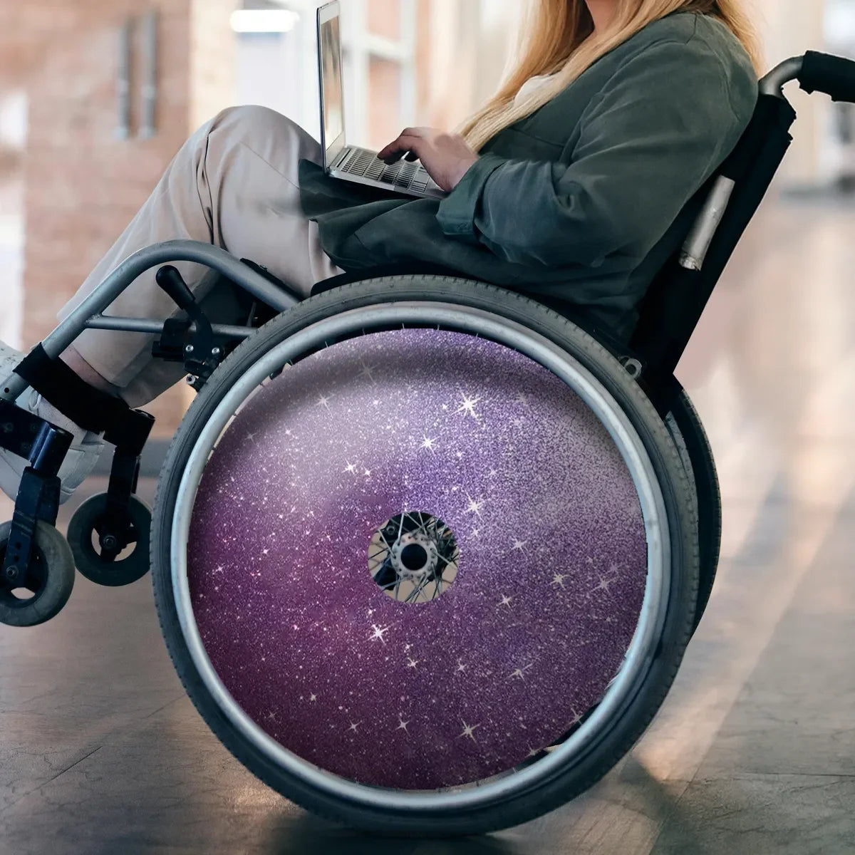 Violetter Galaxy-Rollstuhl-Speichenschutz mit Sternendesign, genutzt von einer Person am Laptop