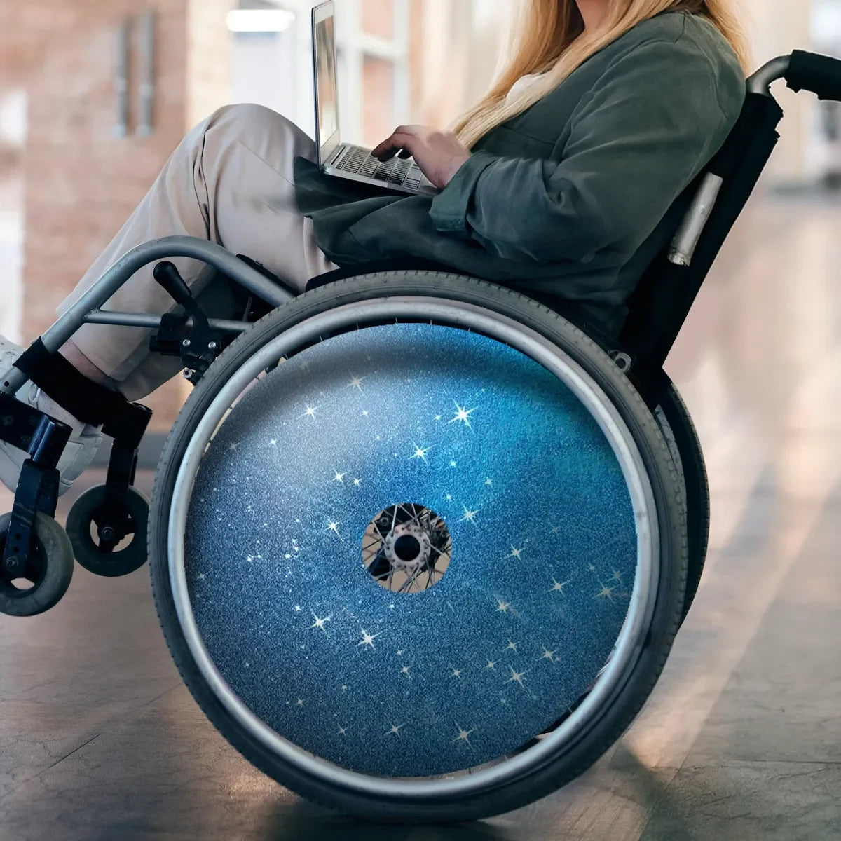 Rollstuhl mit Galaxy-Speichenschutz, Nutzer tippt auf einem Laptop