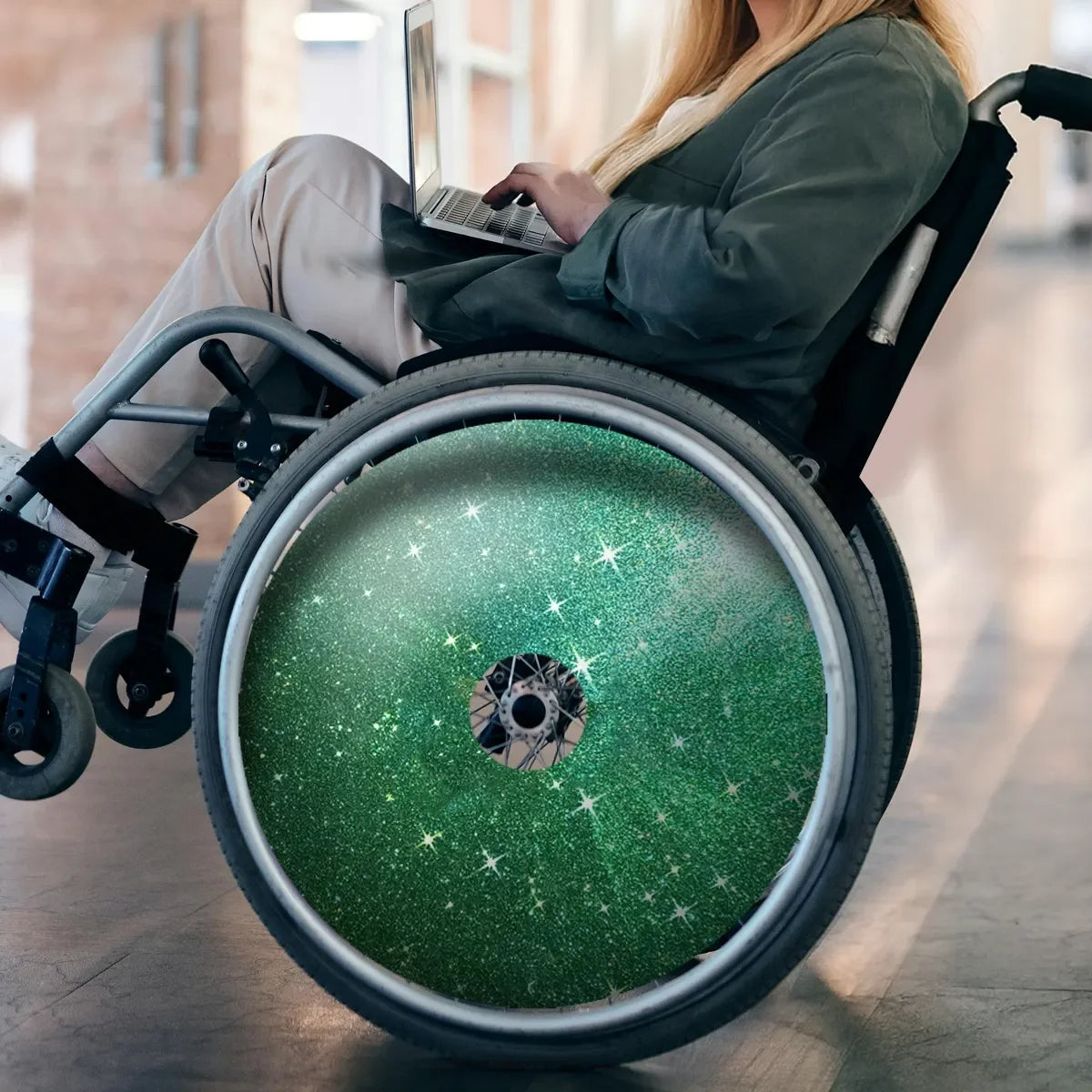 Green glitter wheelchair spoke guard with star design, user typing on laptop