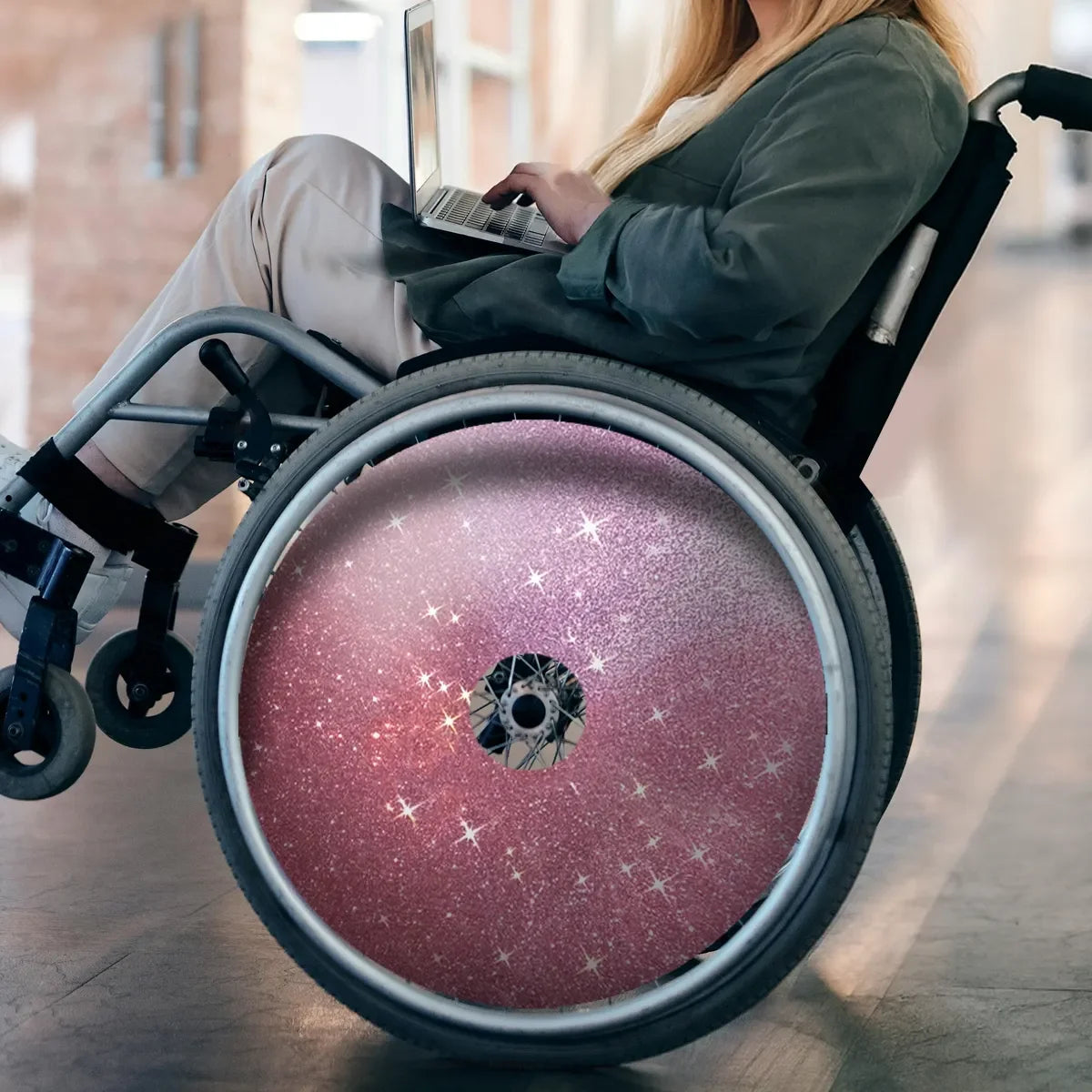 Pink glitter wheelchair spoke guard with star design, used by person typing on laptop