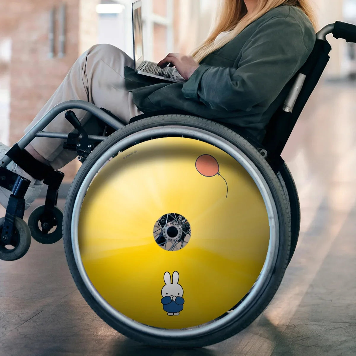 Woman in wheelchair with yellow Miffy cartoon spoke guard featuring bunny and balloon design