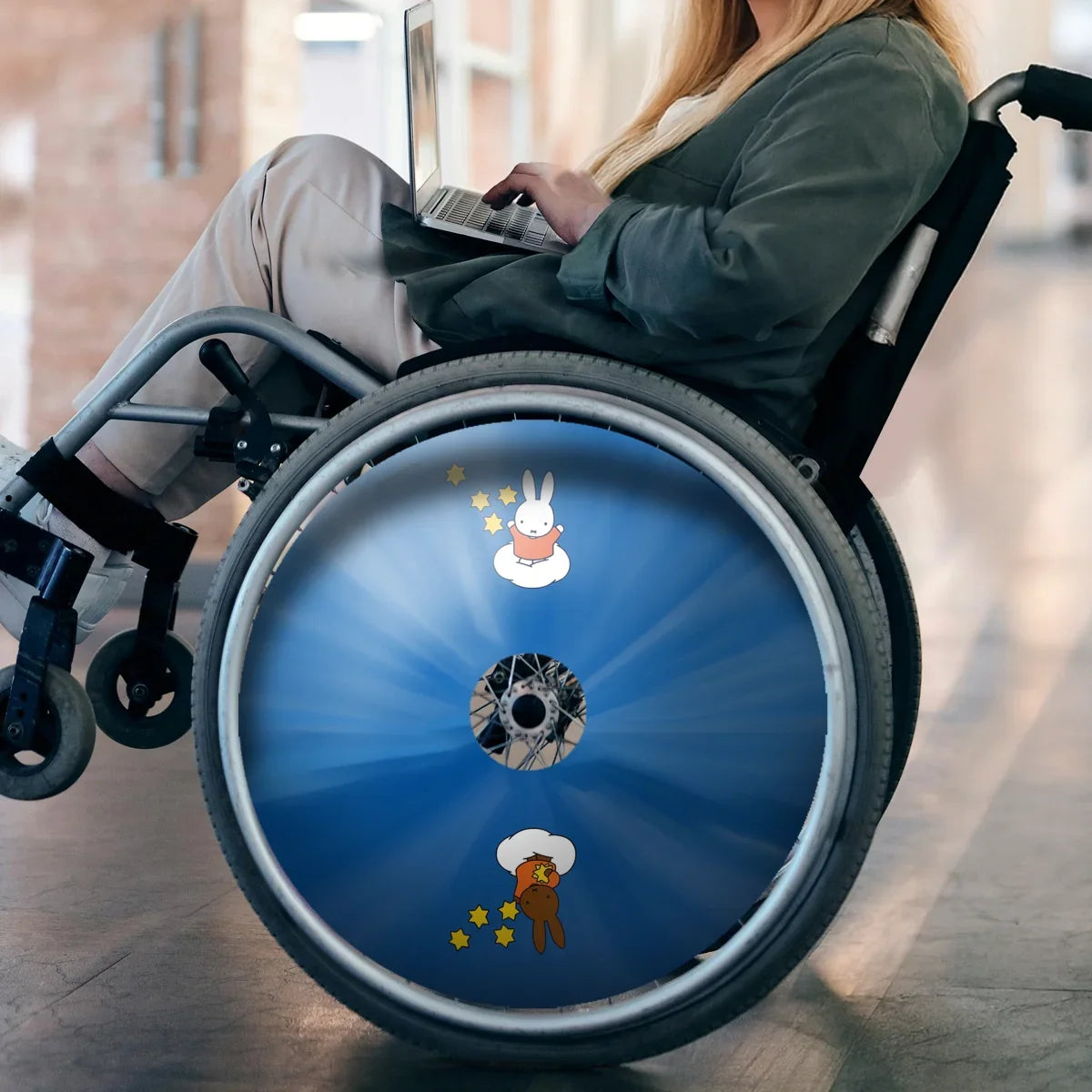 Woman using wheelchair with blue spoke guard featuring Miffy and Melanie cartoon design